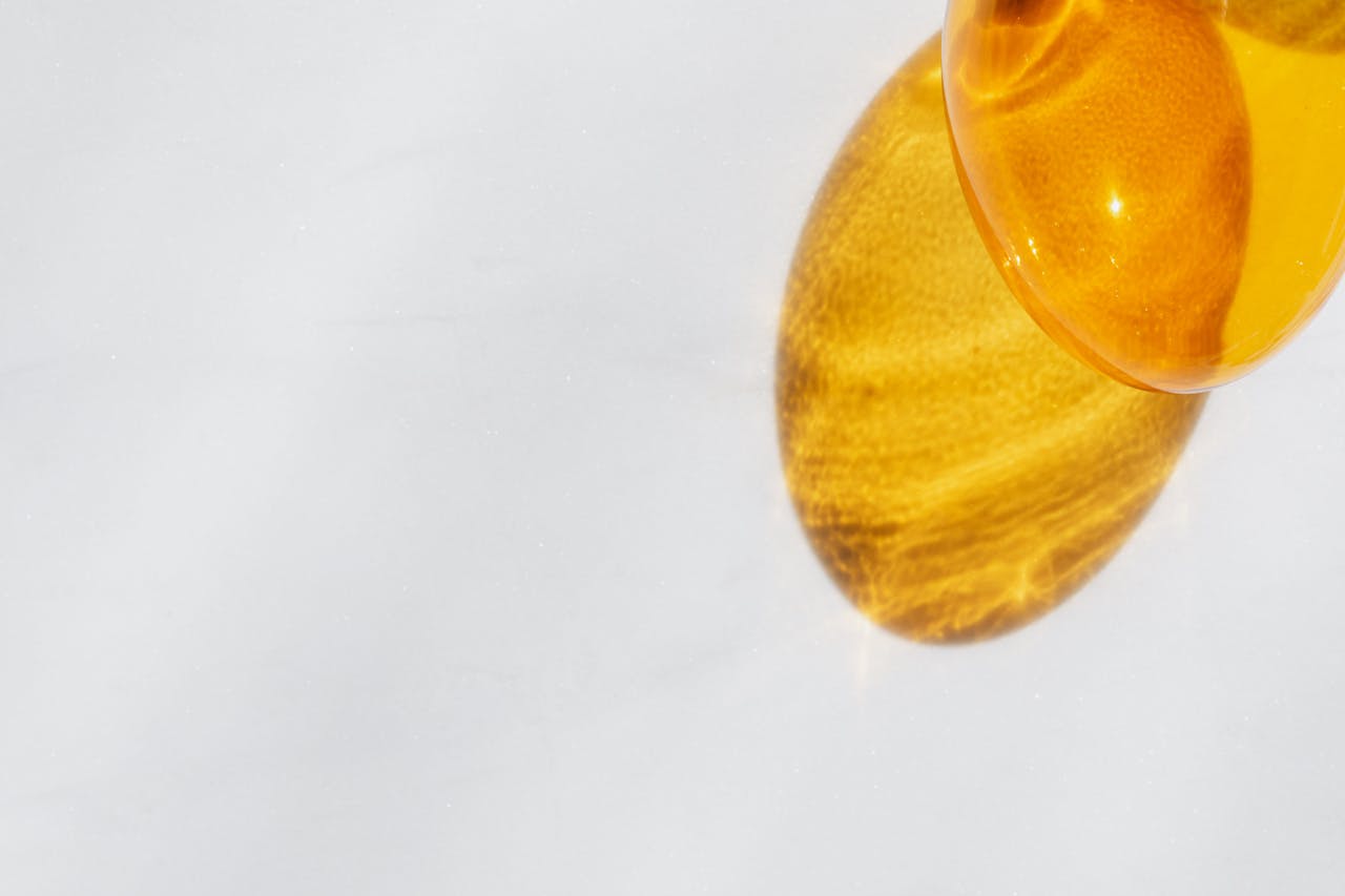 Minimalist composition with a sunlit yellow glass casting a shadow on a white surface.
